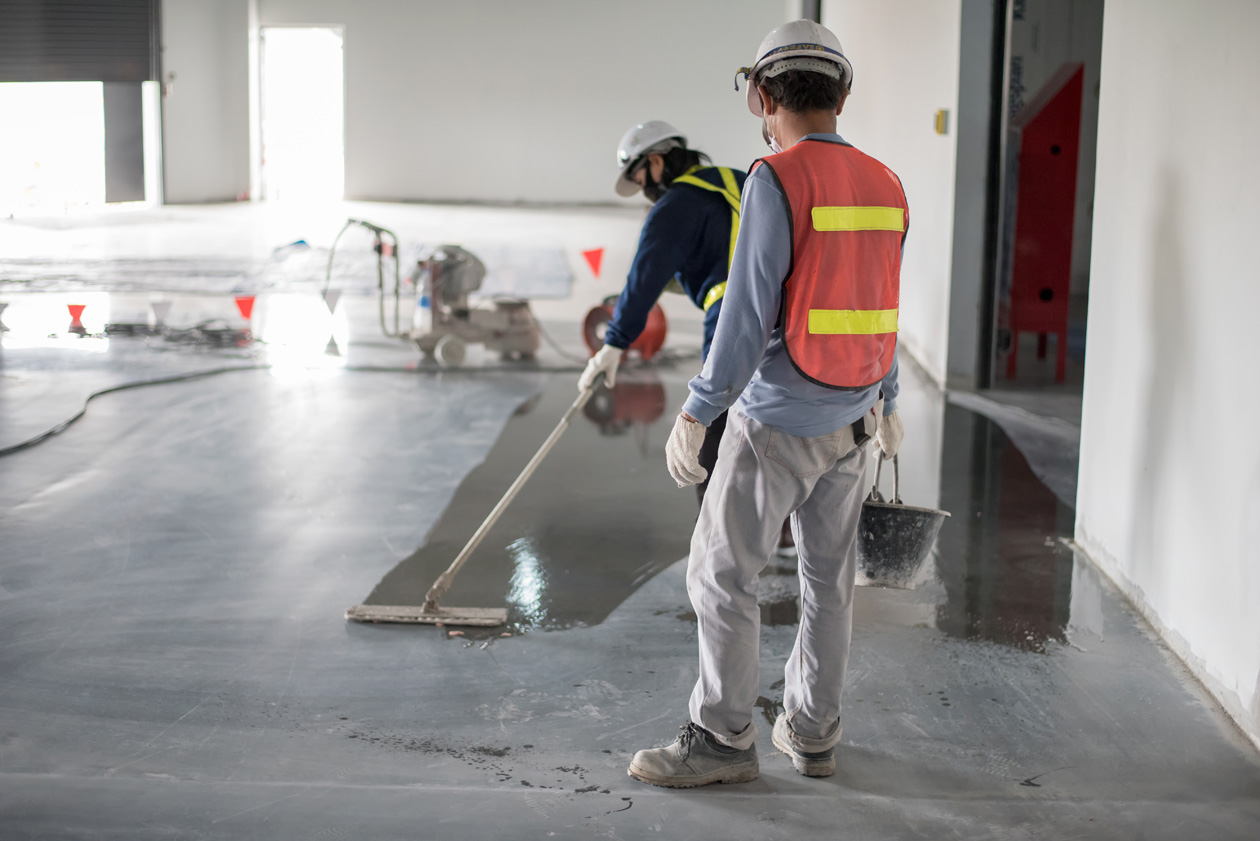 Workers in safety gear performing industrial floor cleaning and polishing at a large facility